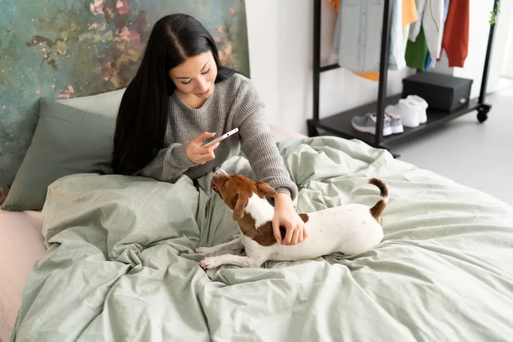 a woman laying on a bed petting a dog