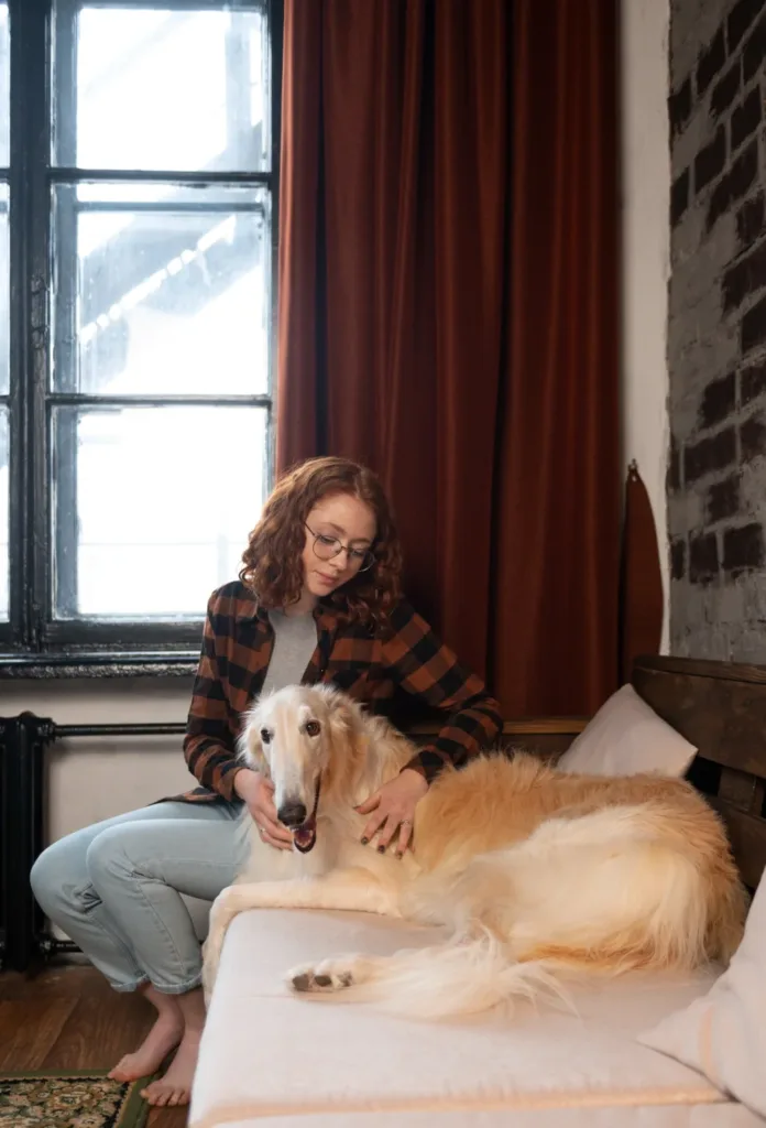 a woman sitting on a bed petting a dog