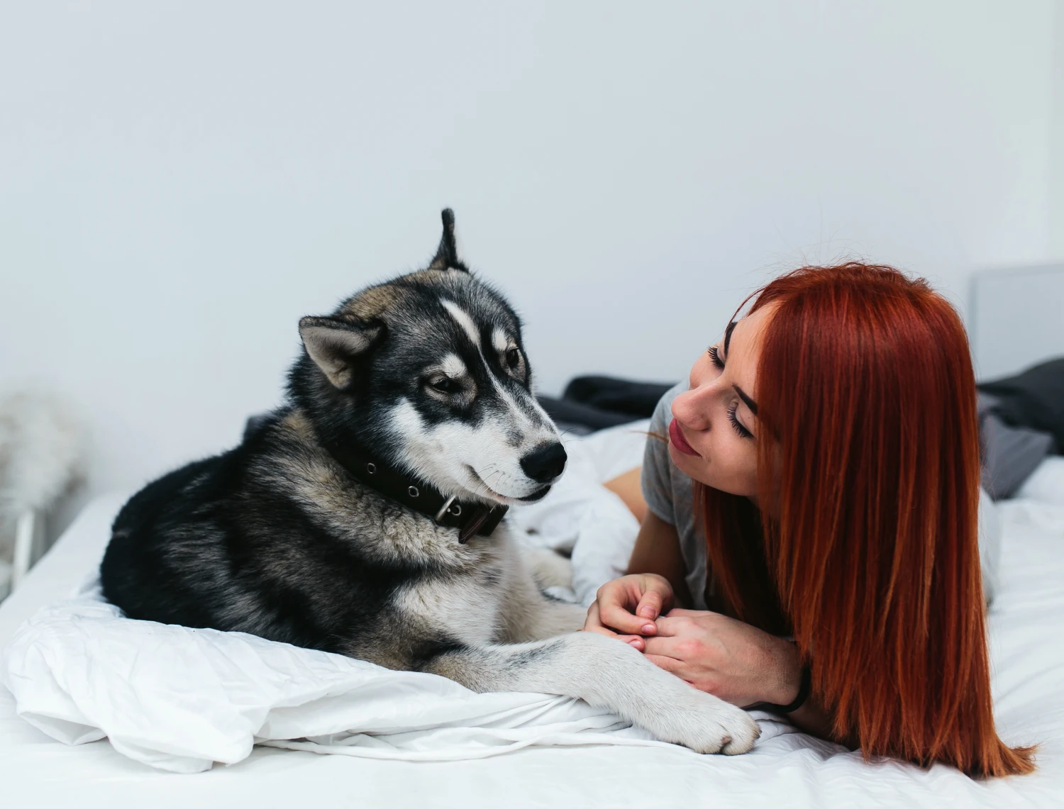 a woman laying on a bed next to a dog