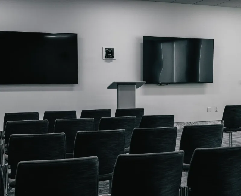 a room filled with black chairs and a projector screen